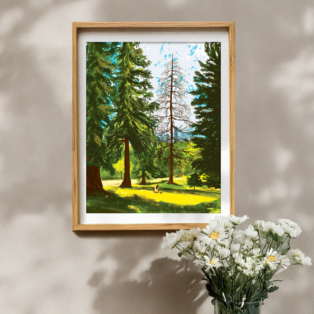 Framed print of a Nathan Gowsell Creative art piece called Amongst the Trees, hung on a wall with a vase of white flowers in the foreground.